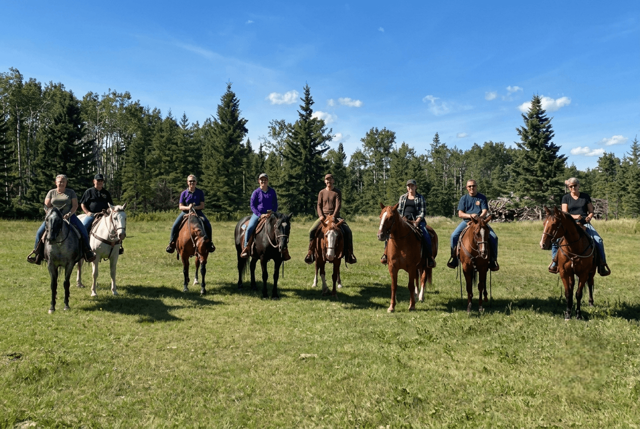 group-riding-horses-in-grassy-field A group of people riding horses lined up in an open field.