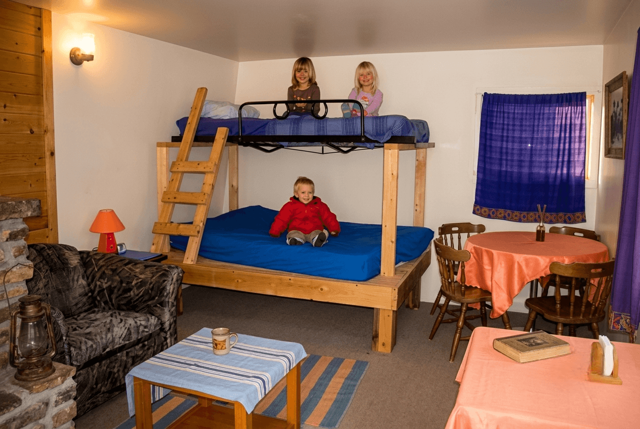 kids-on-bunk-beds-in-cabin-room Three children on wooden bunk beds inside a cabin room.